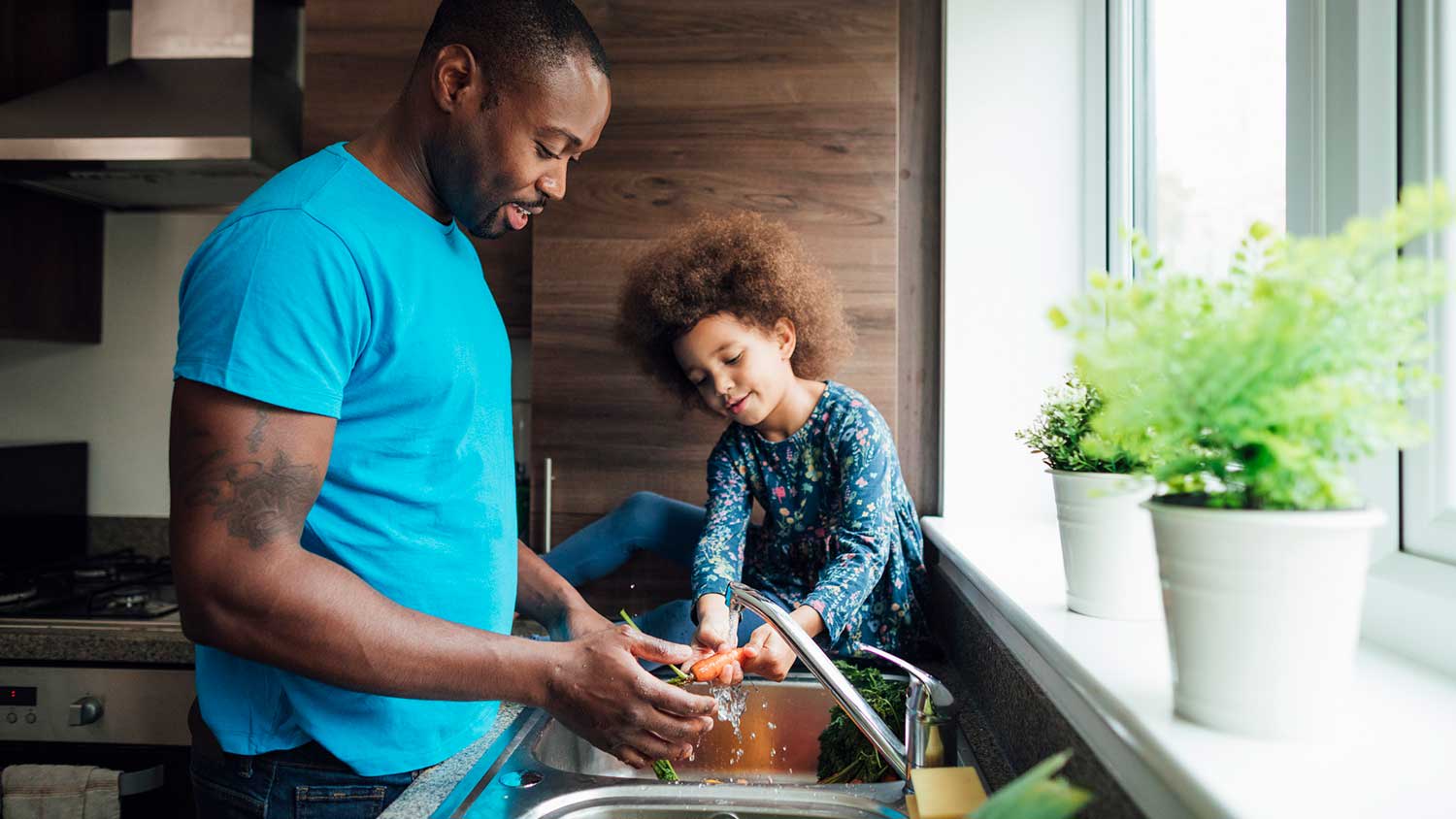 Young daughter helping dad washing veggies