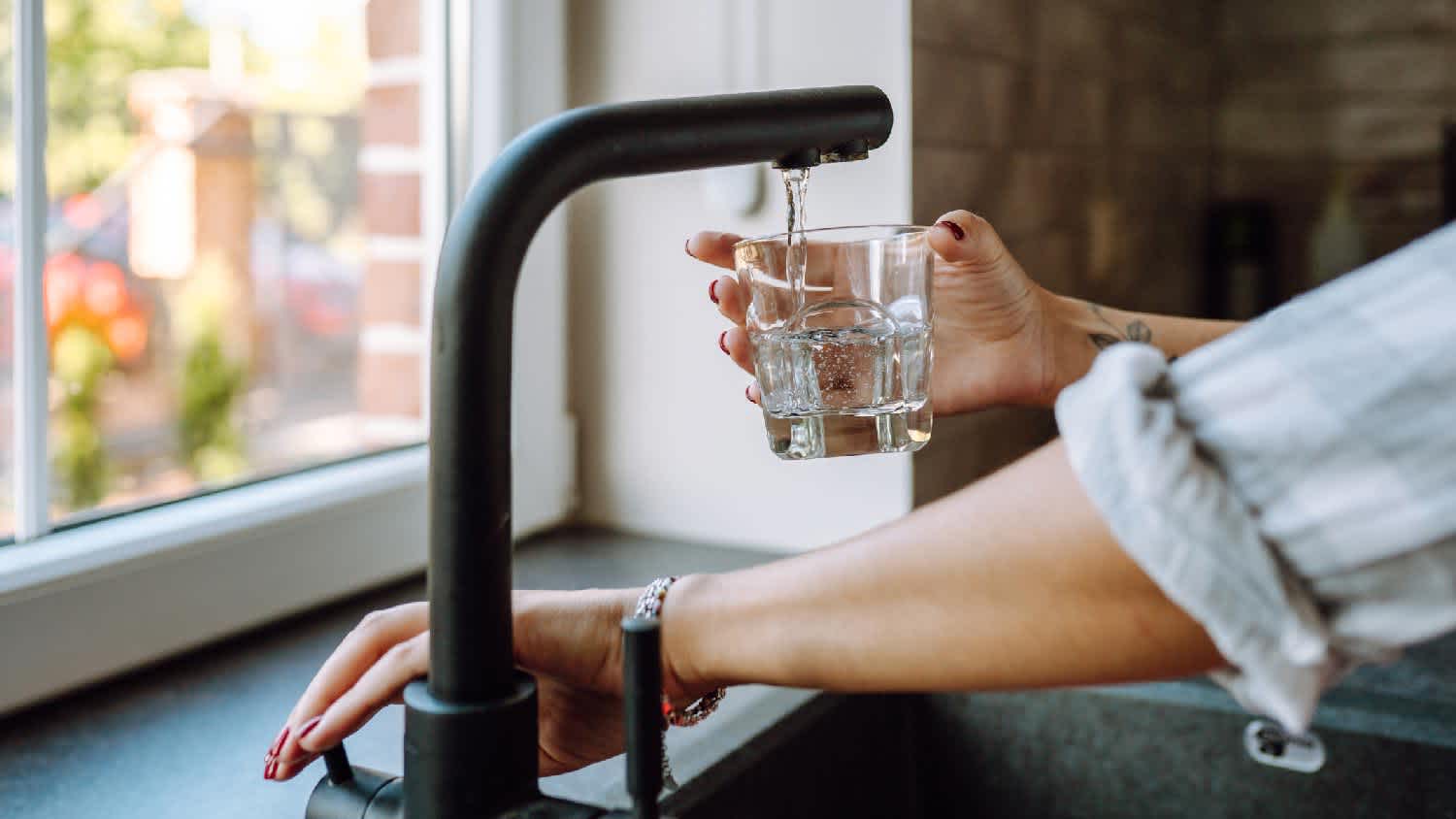 A woman pouring tap water in a glass