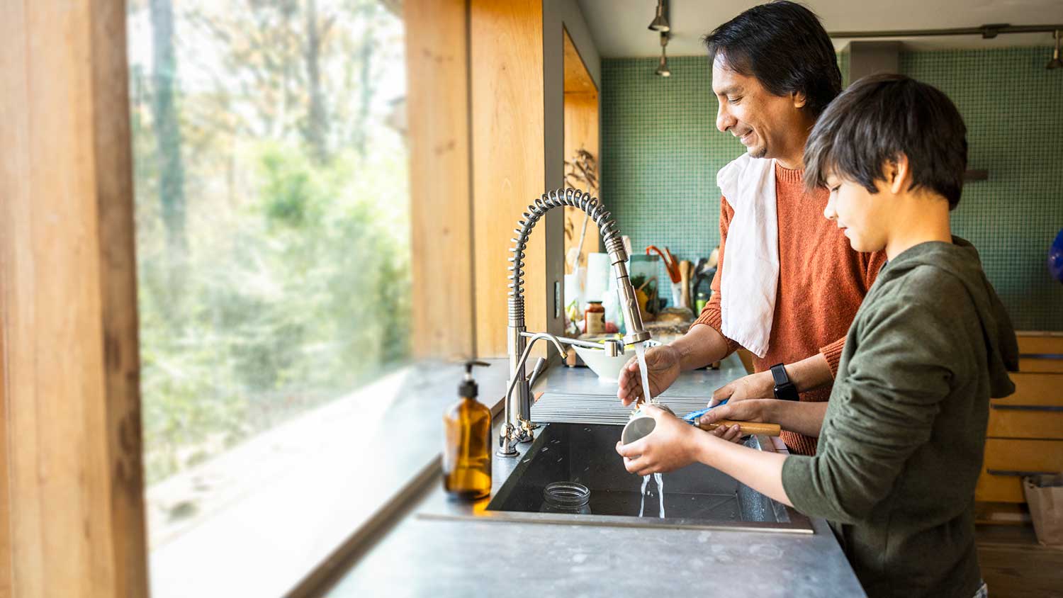 Mother and son washing dishes together