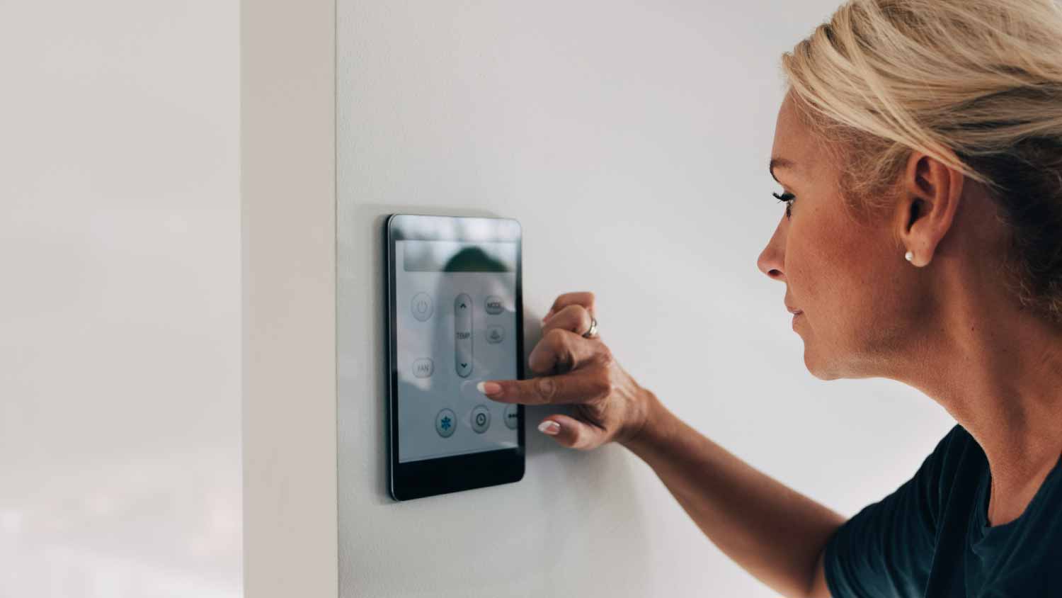 woman adjusting thermostat