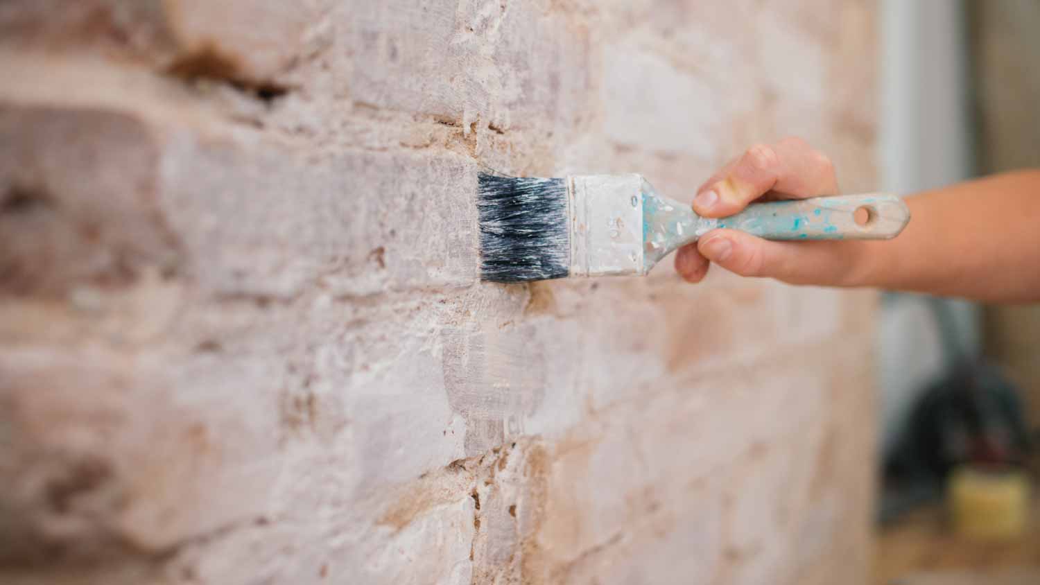 A woman painting a brick wall