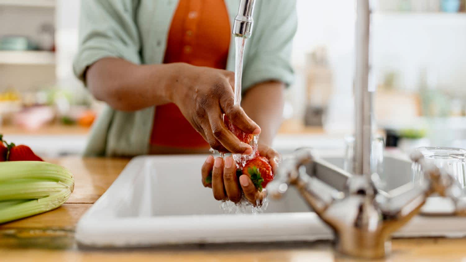 A woman rinsing strawberries in the kitchen sink