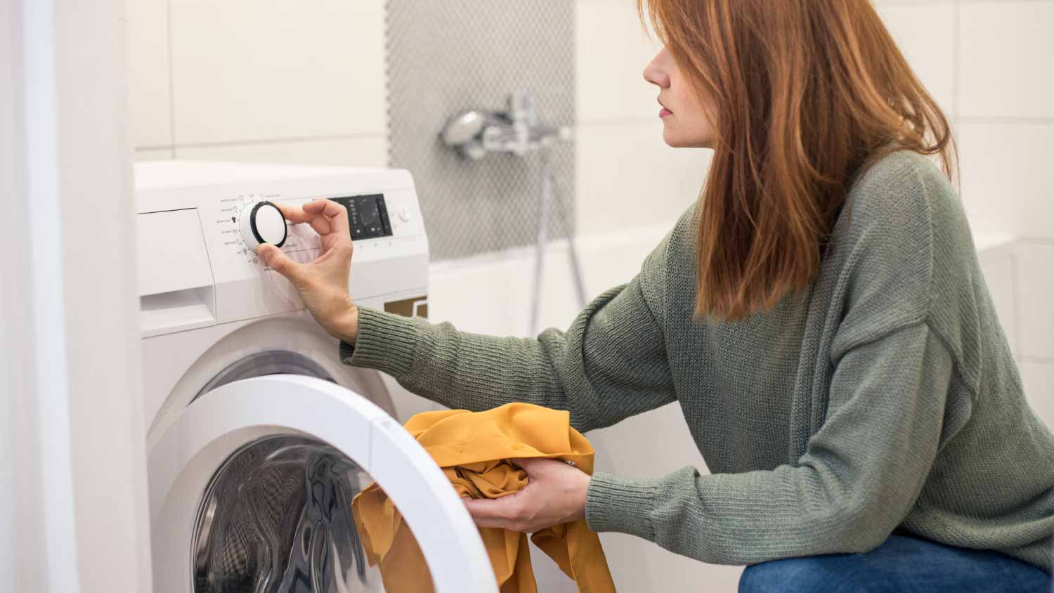 A person setting the washing machine while doing laundry.
