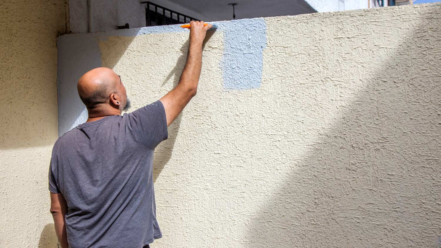 Man painting textured wall