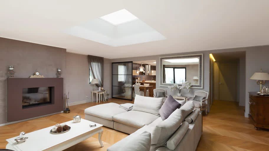 A living room with a corner sofa and a skylight above