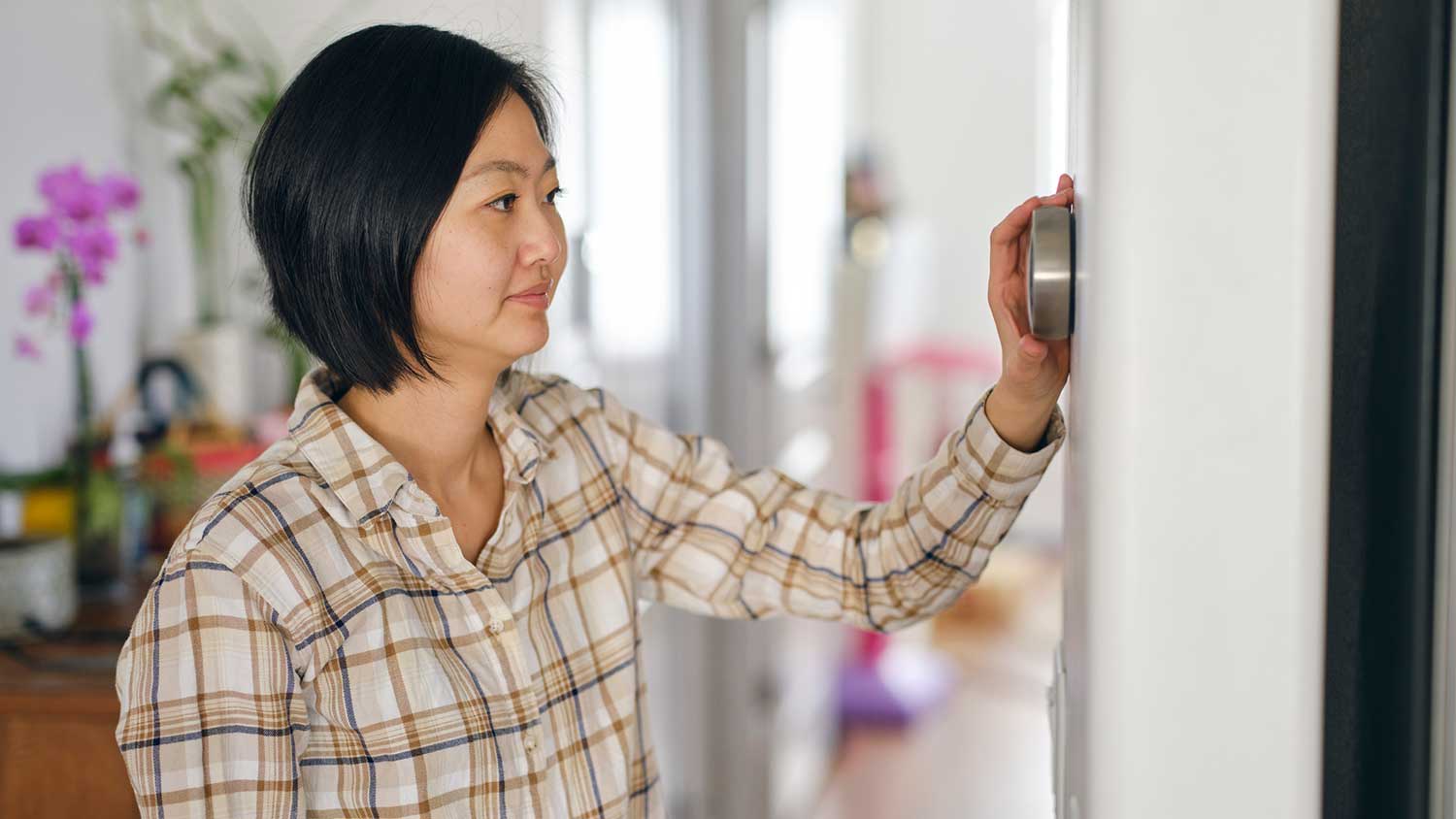 Man wearing a sweater adjusting thermostat