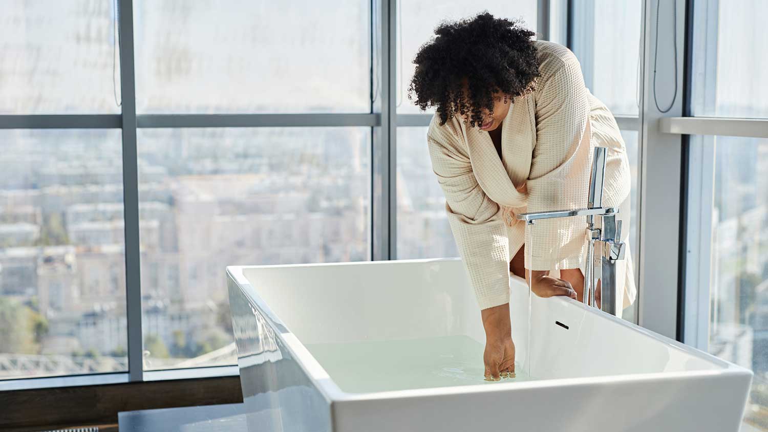 Woman in a robe filling up a tub with water