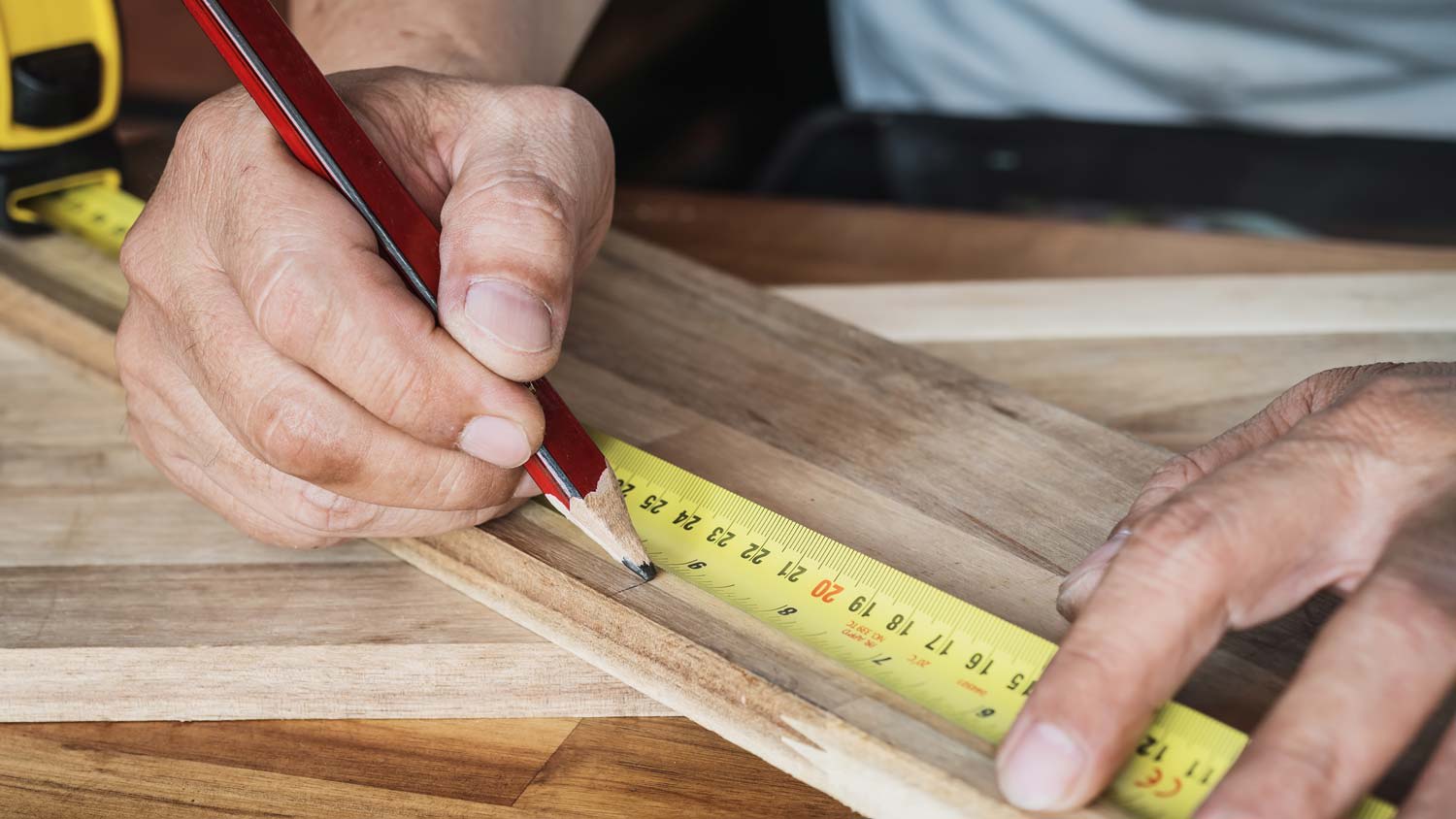 man measuring piece of wood