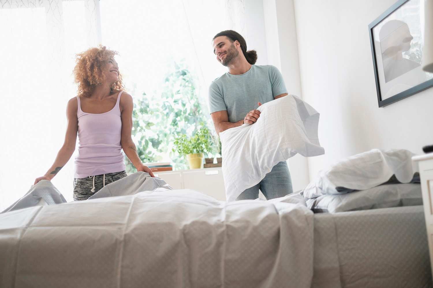 Young couple making bed in the morning