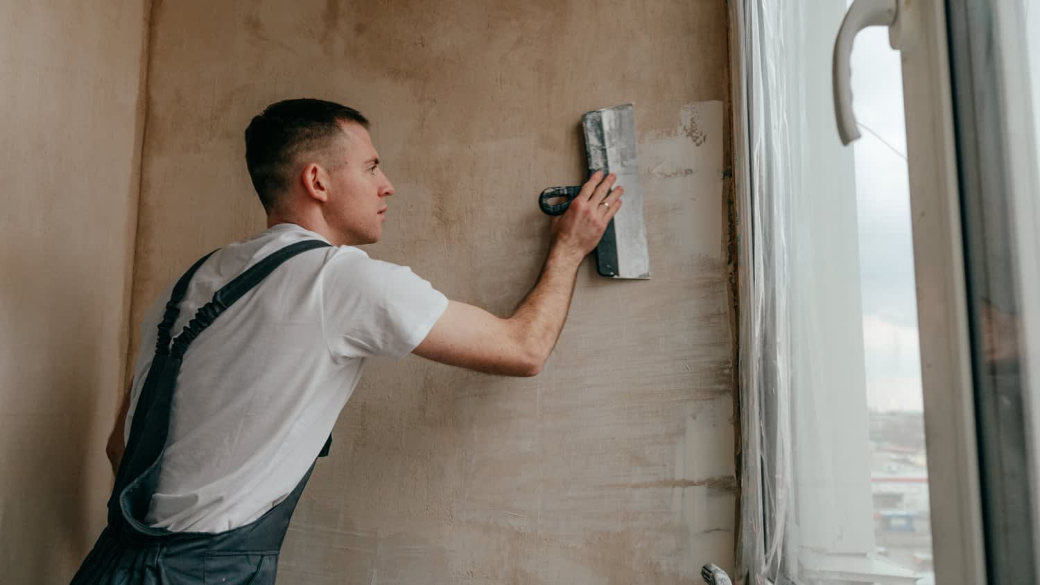 Worker applying putty mortar on the balcony wall