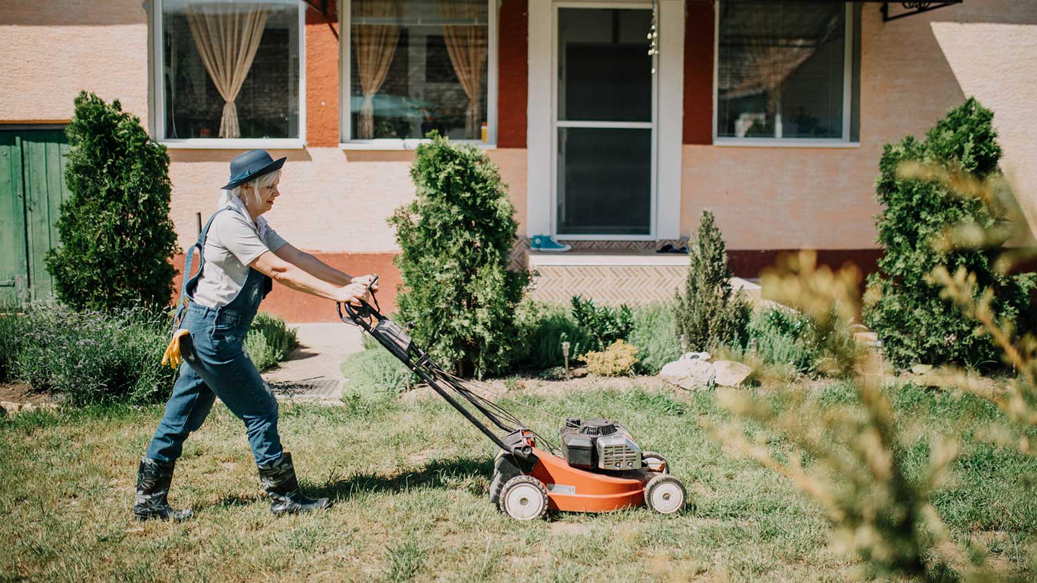 A woman mowing her lawn in the backyard