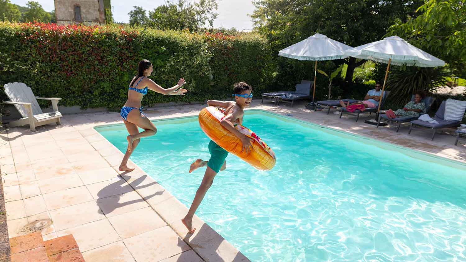 Brother and sister jumping into the pool