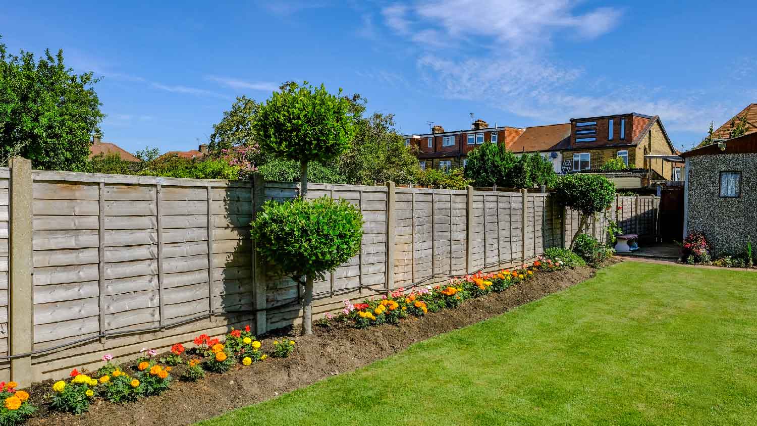 A yard with a wooden fence and flower beds