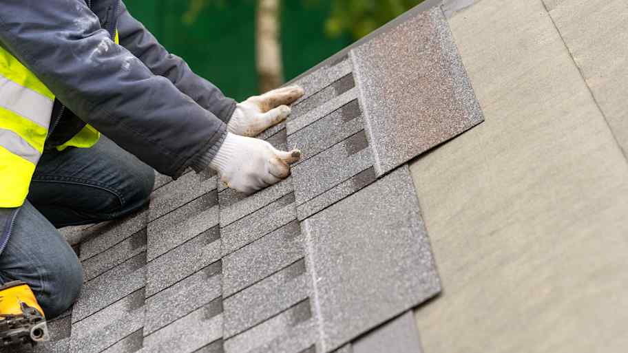Contractor installing asphalt shingles on a roof