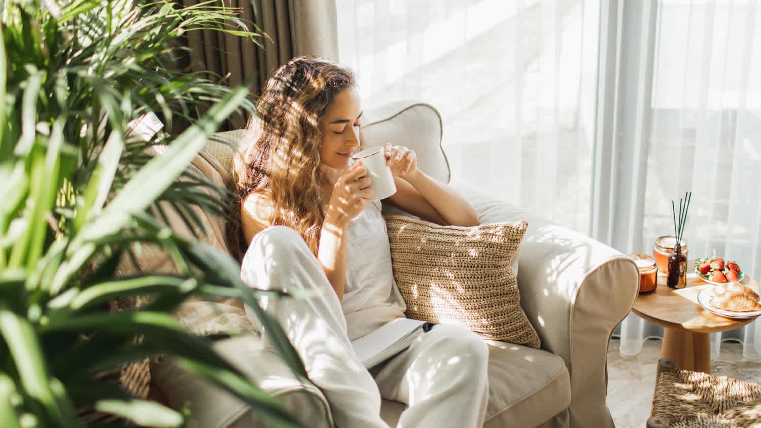 Woman at home reading book and drinking coffee