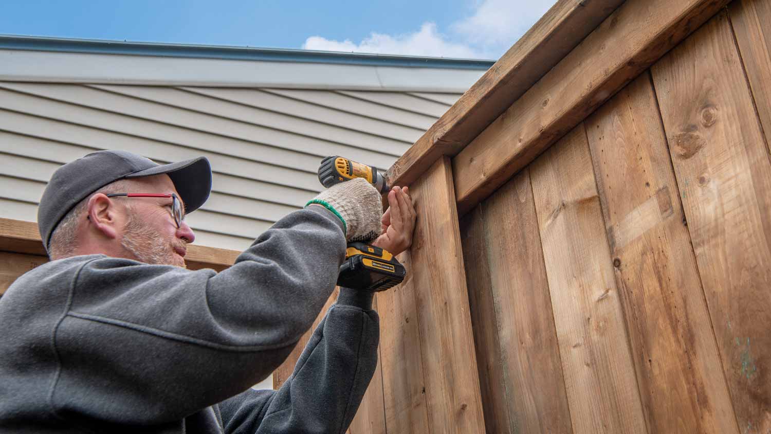 Man installing wooden fence