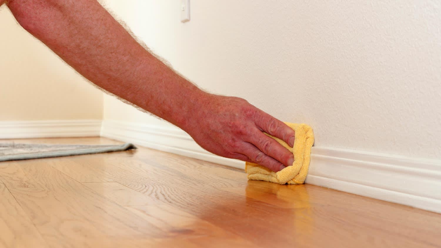 A person cleaning a baseboard