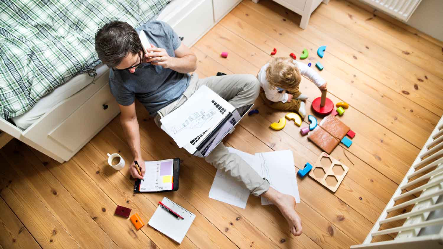 A man working while his kid playing on the floor