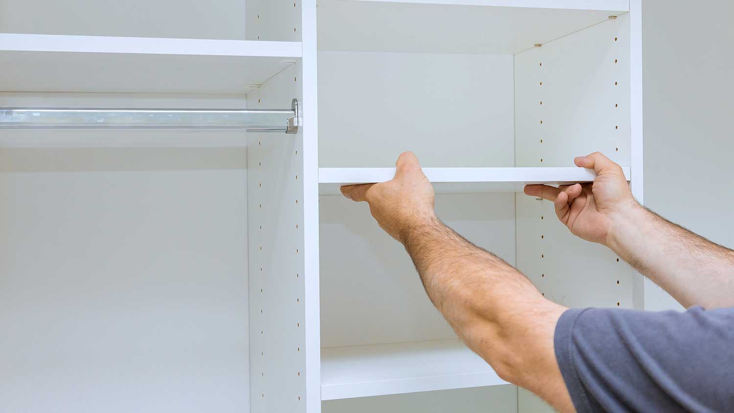 Person adjusting a shelf in an empty closet