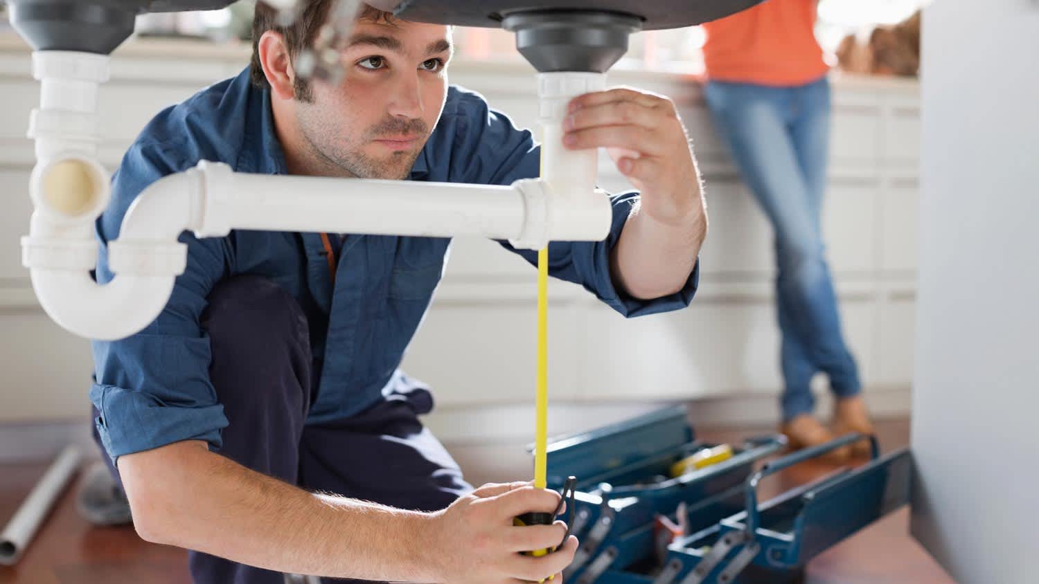 Plumber working on pipes in the kitchen