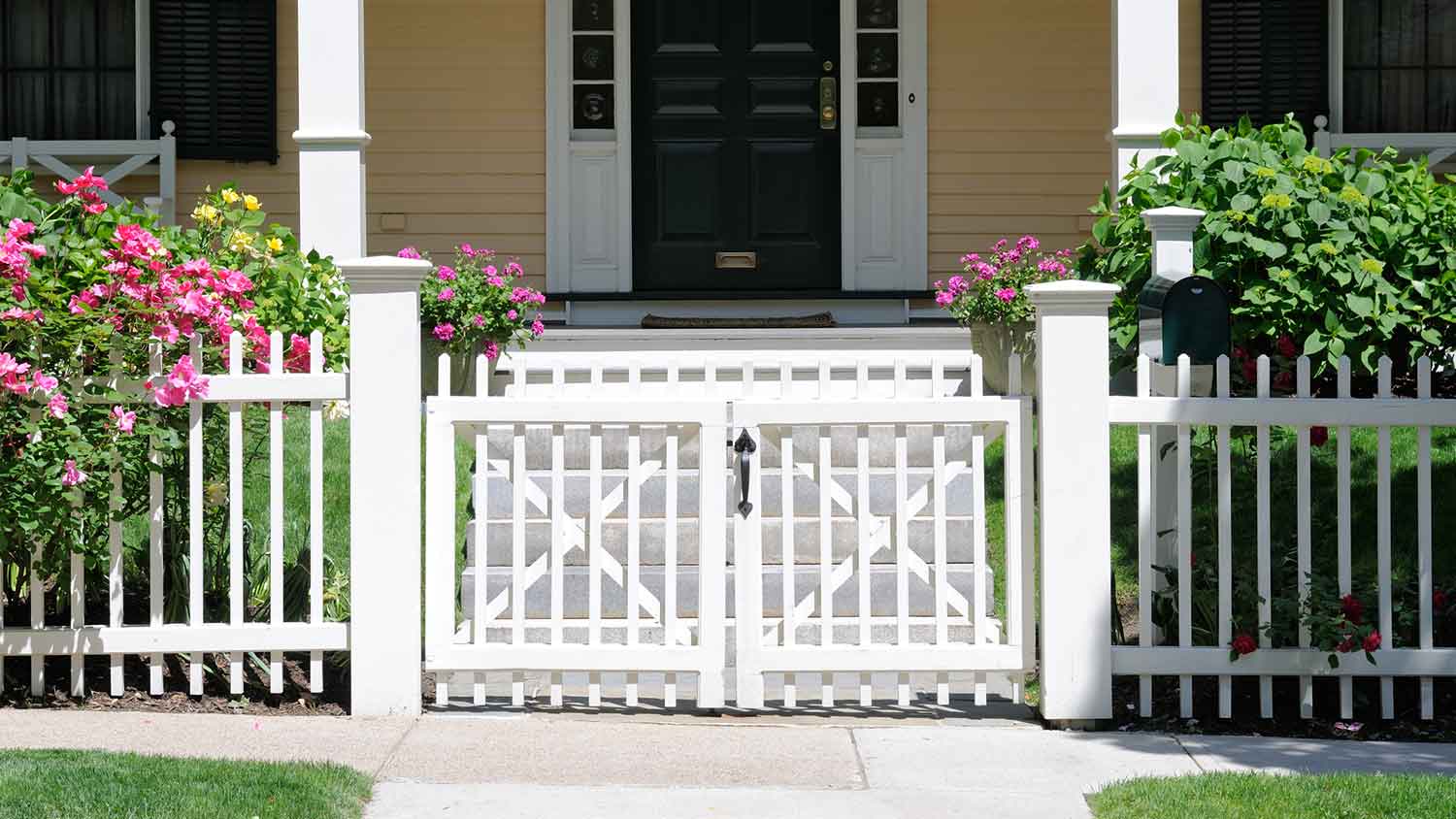 House with a white fence gate by the sidewalk
