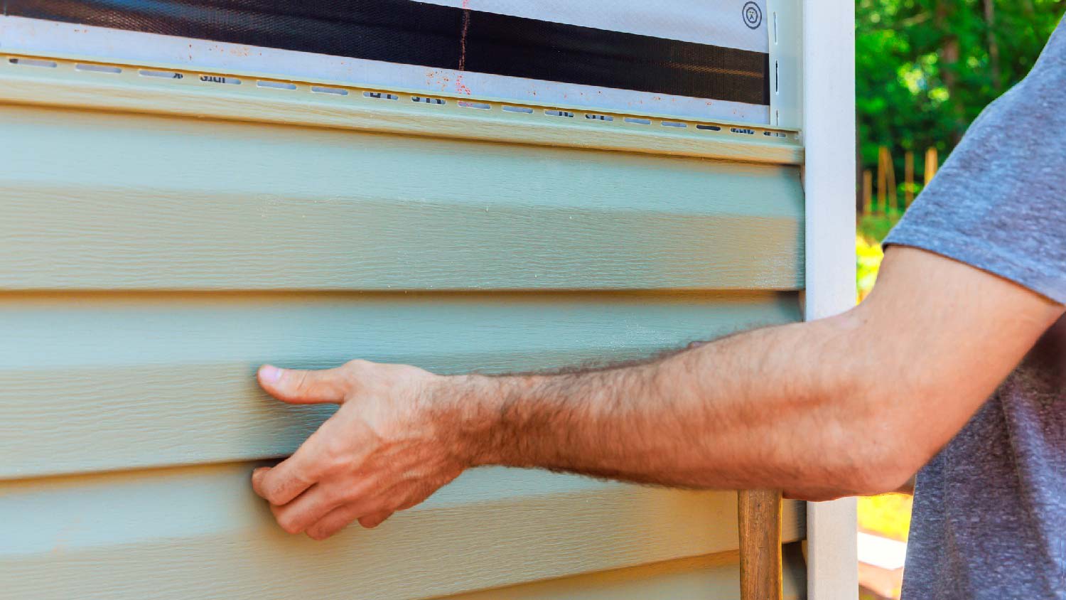 Close-up of a person replacing a house’s siding