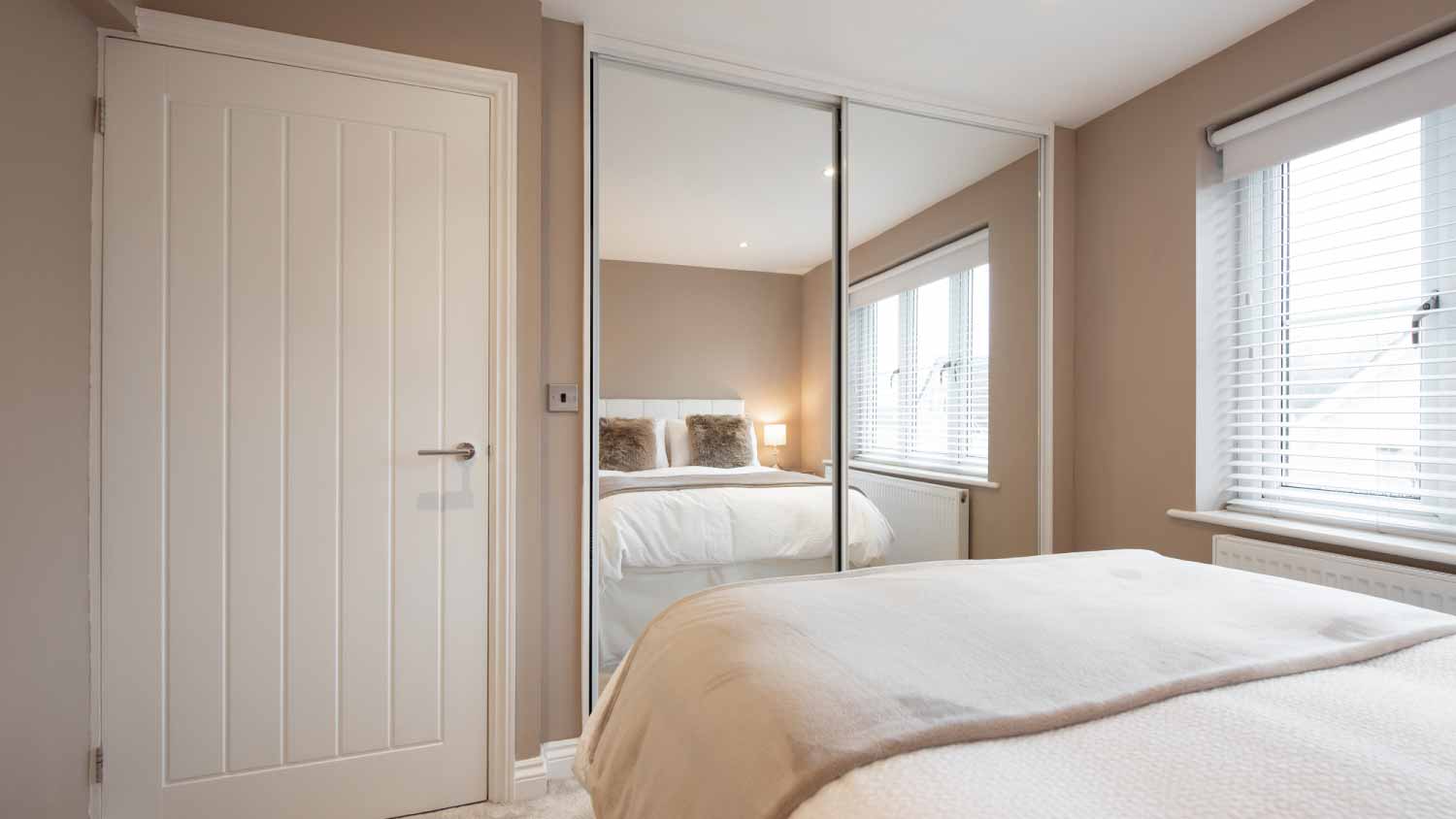 Interior of bedroom with large mirror doors next to the bed