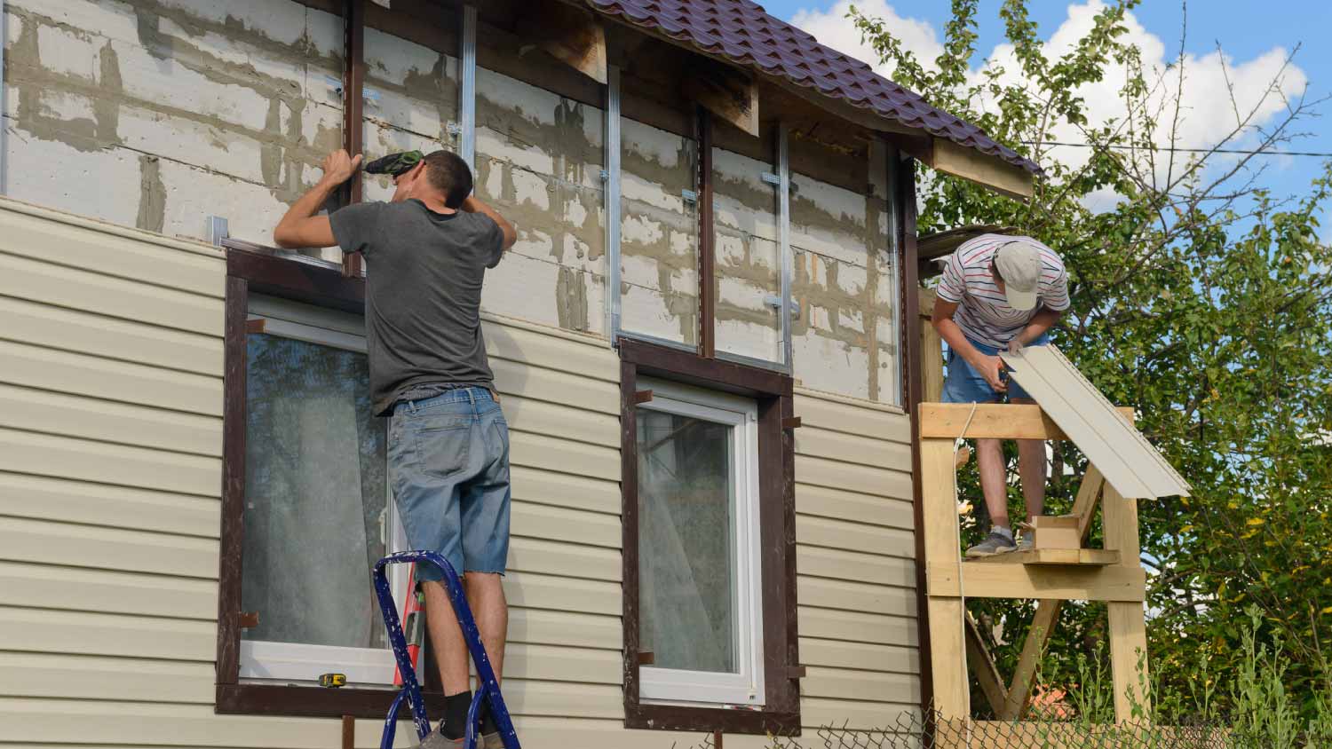 Two workers installing vinyl siding