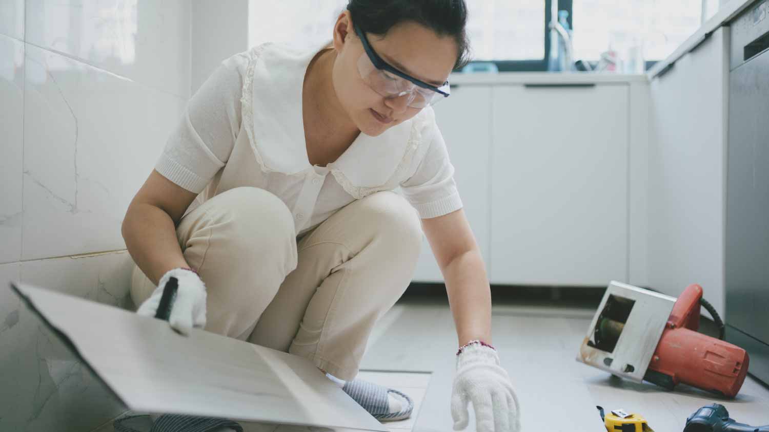 Detail of a woman’s hands installing laminate flooring