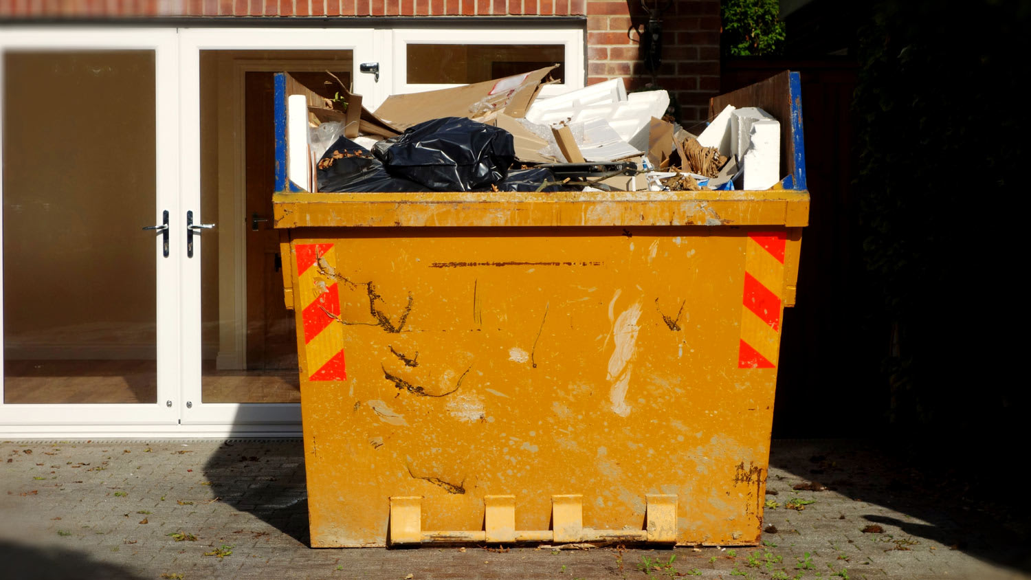 Full hired industrial skip filled with garbage from house clearance