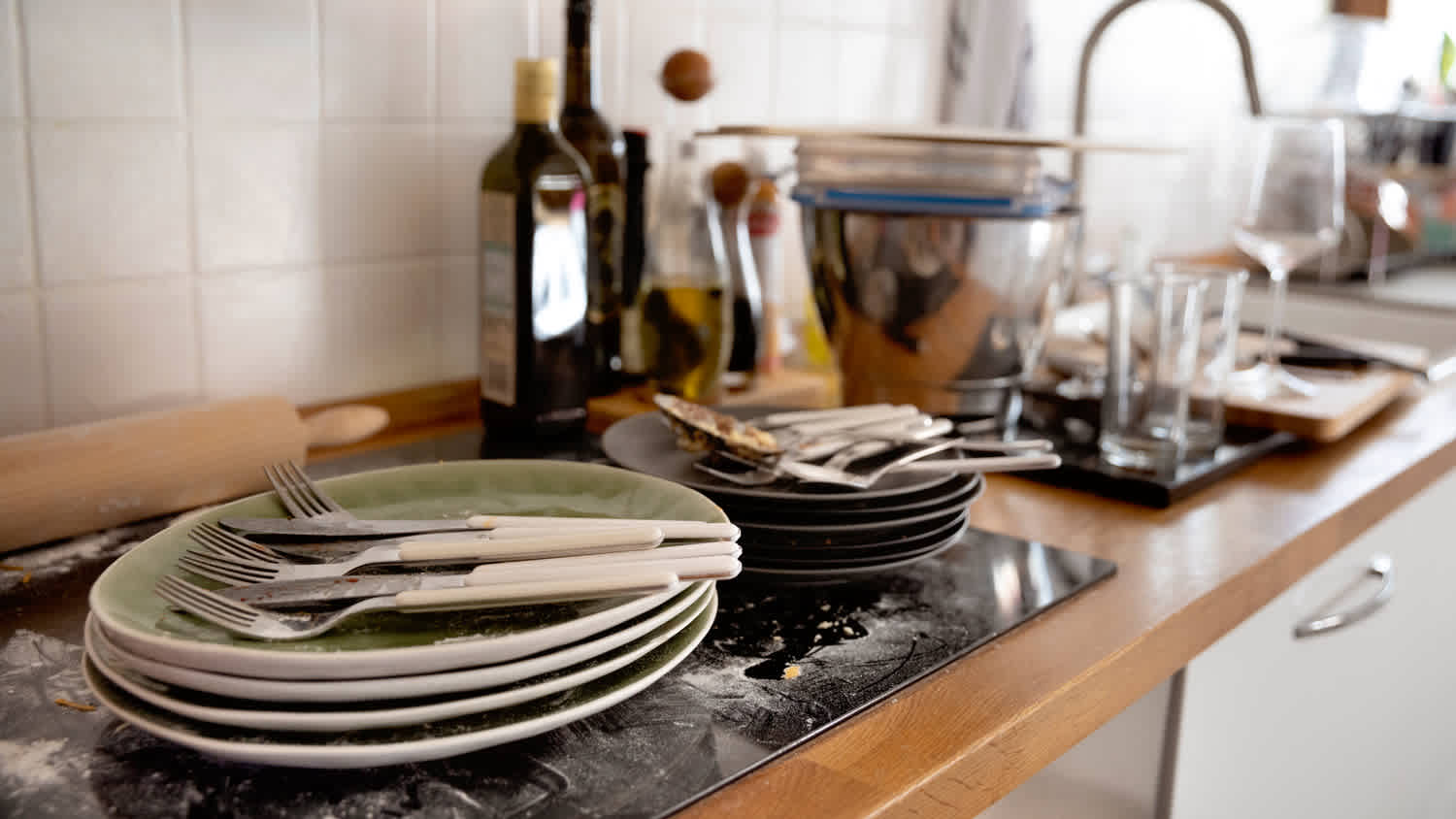 Dirty dishes and cutlery on a messy kitchen counter