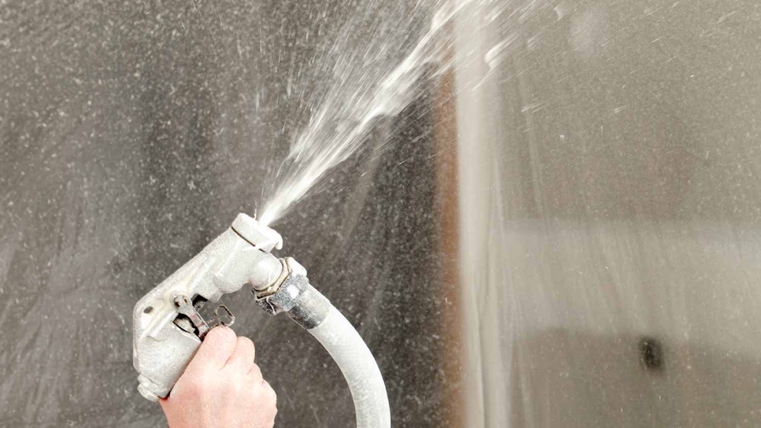Worker spraying drywall mud