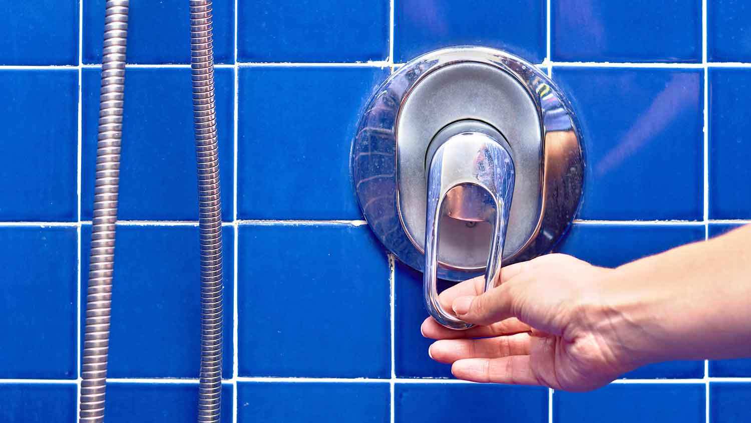 Adjusting shower valve installed in a blue tile shower