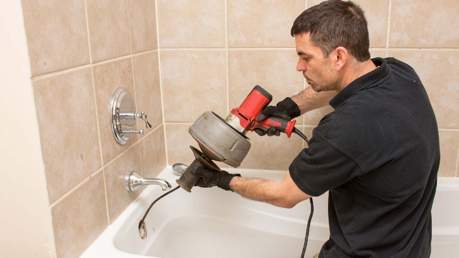 A professional unclogging a bathtub