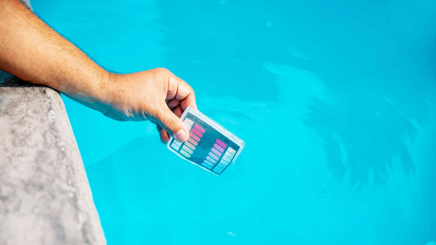 A person testing a pool’s pH