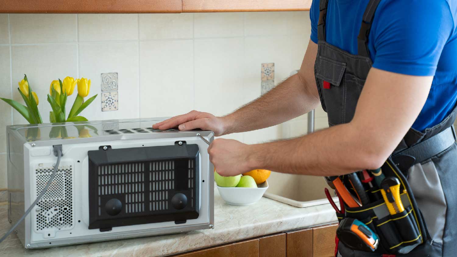 A professional repairing a faulty microwave fan