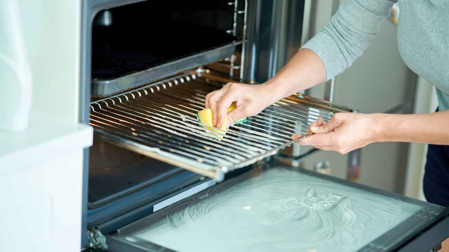 A person deep cleaning an oven rack.