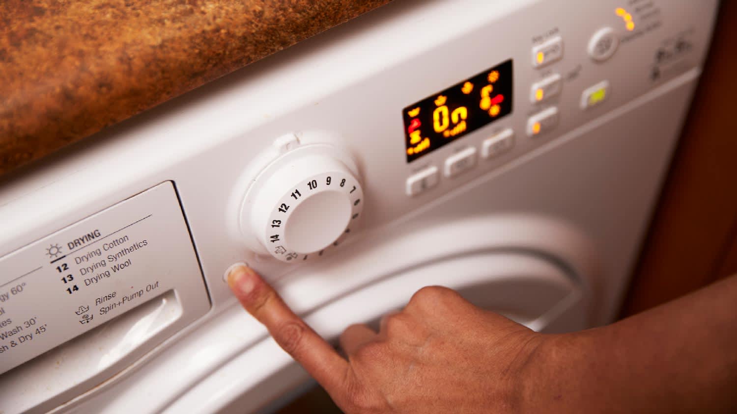 A person turning on a washing machine