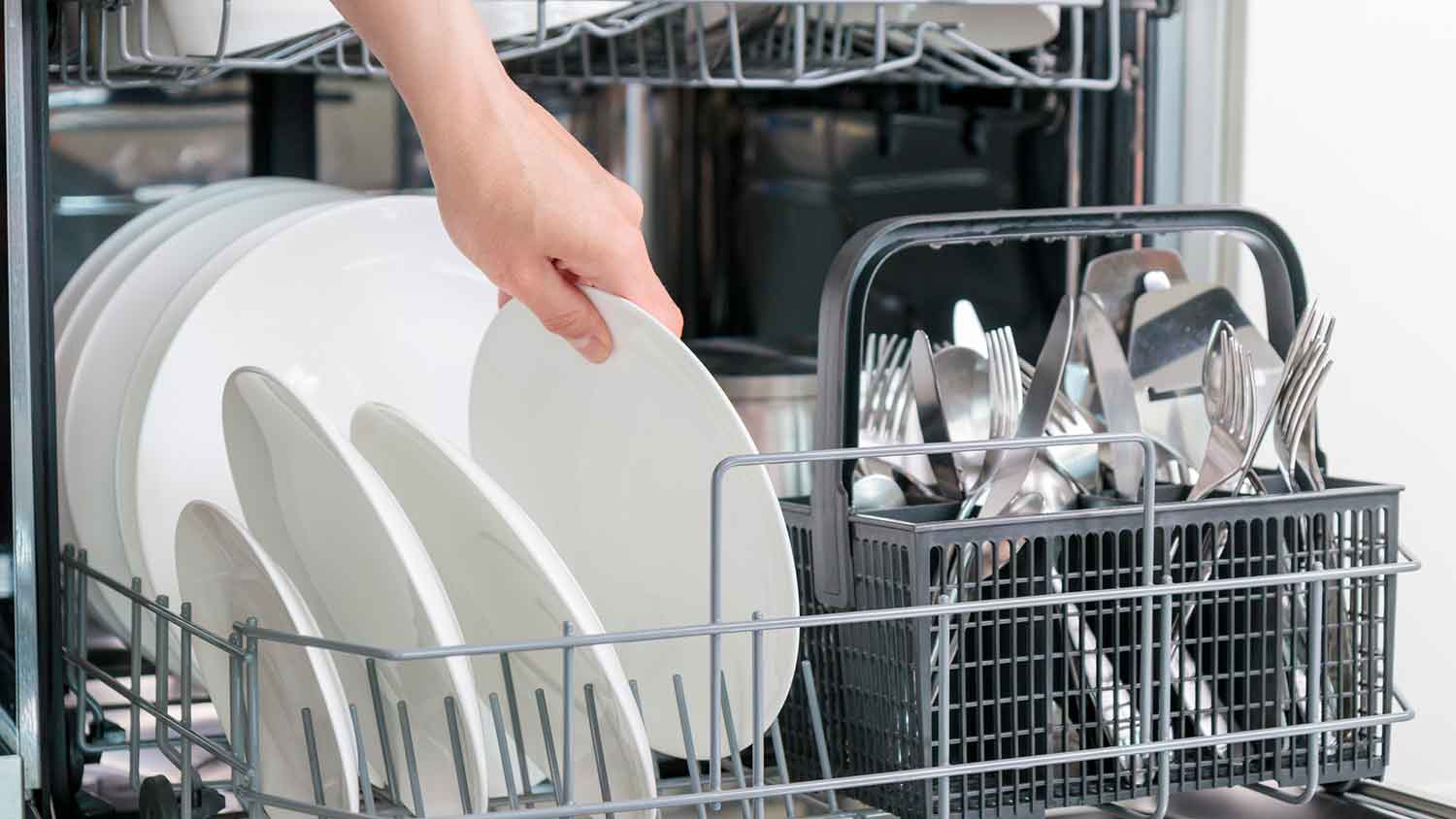 A person placing dishes in a dishwasher