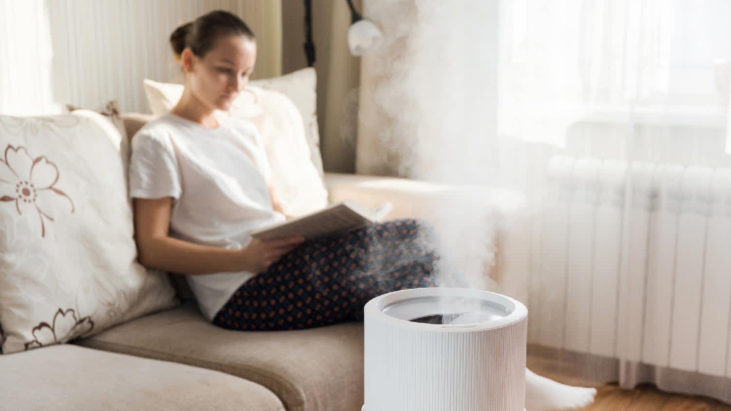 A humidifier operating while a woman reading her book in the background