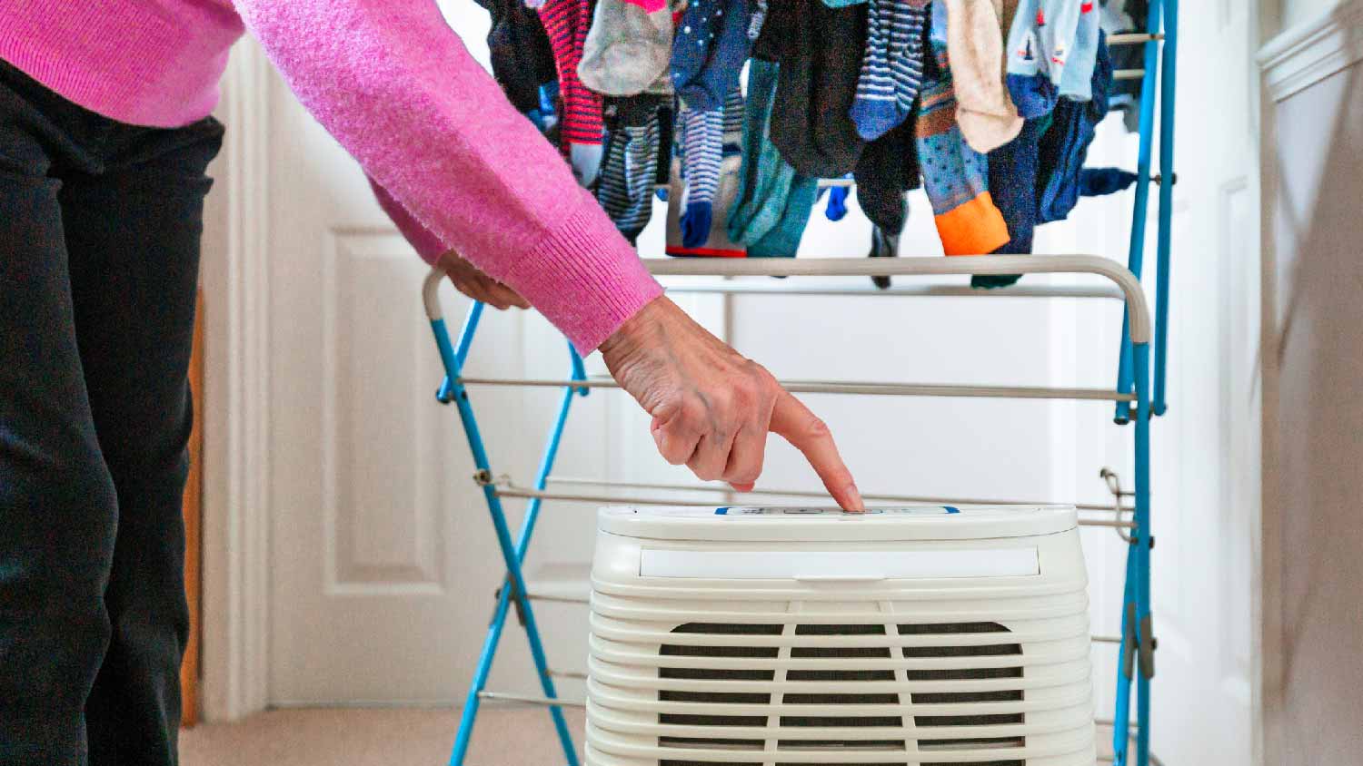 A woman turning on a dehumidifier