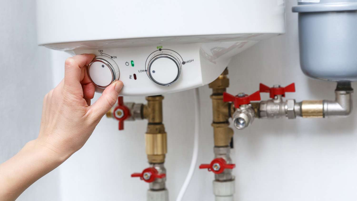 Female hand turning on electric water heater