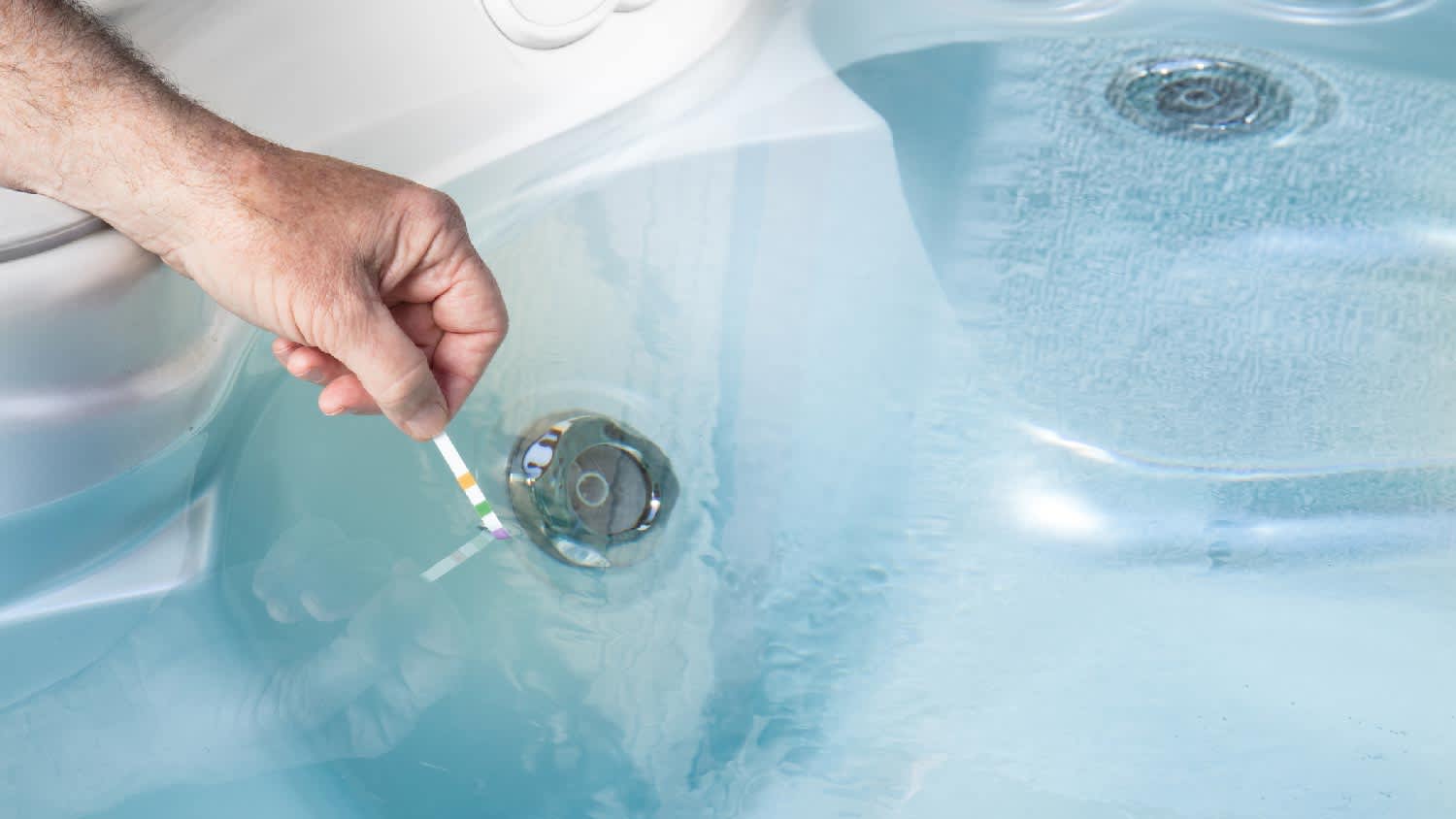A person testing pH levels of a hot tub