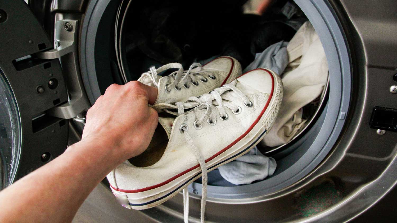 A person placing shoes in a dryer
