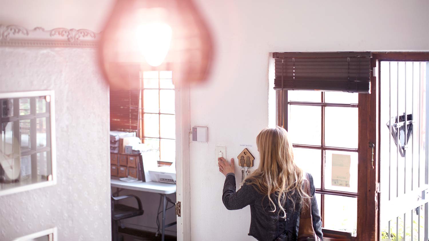 A person turning on a light switch by the doorway