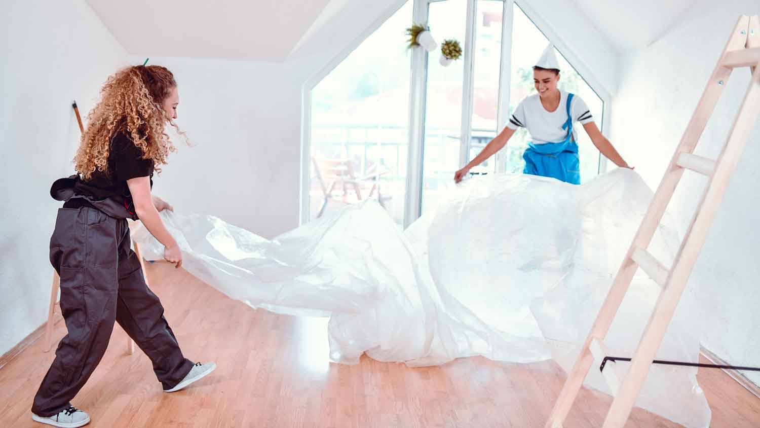 Painters covering the apartment floor with plastic sheeting