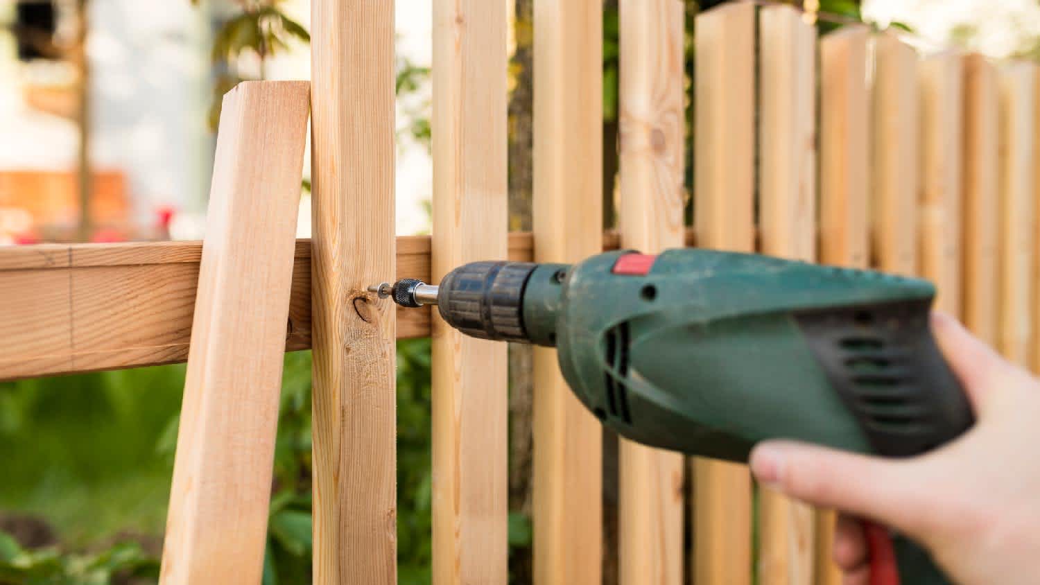 A person repairing a wooden fence