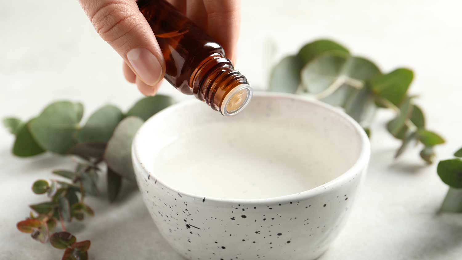 Woman adding eucalyptus essential oil in a bowl