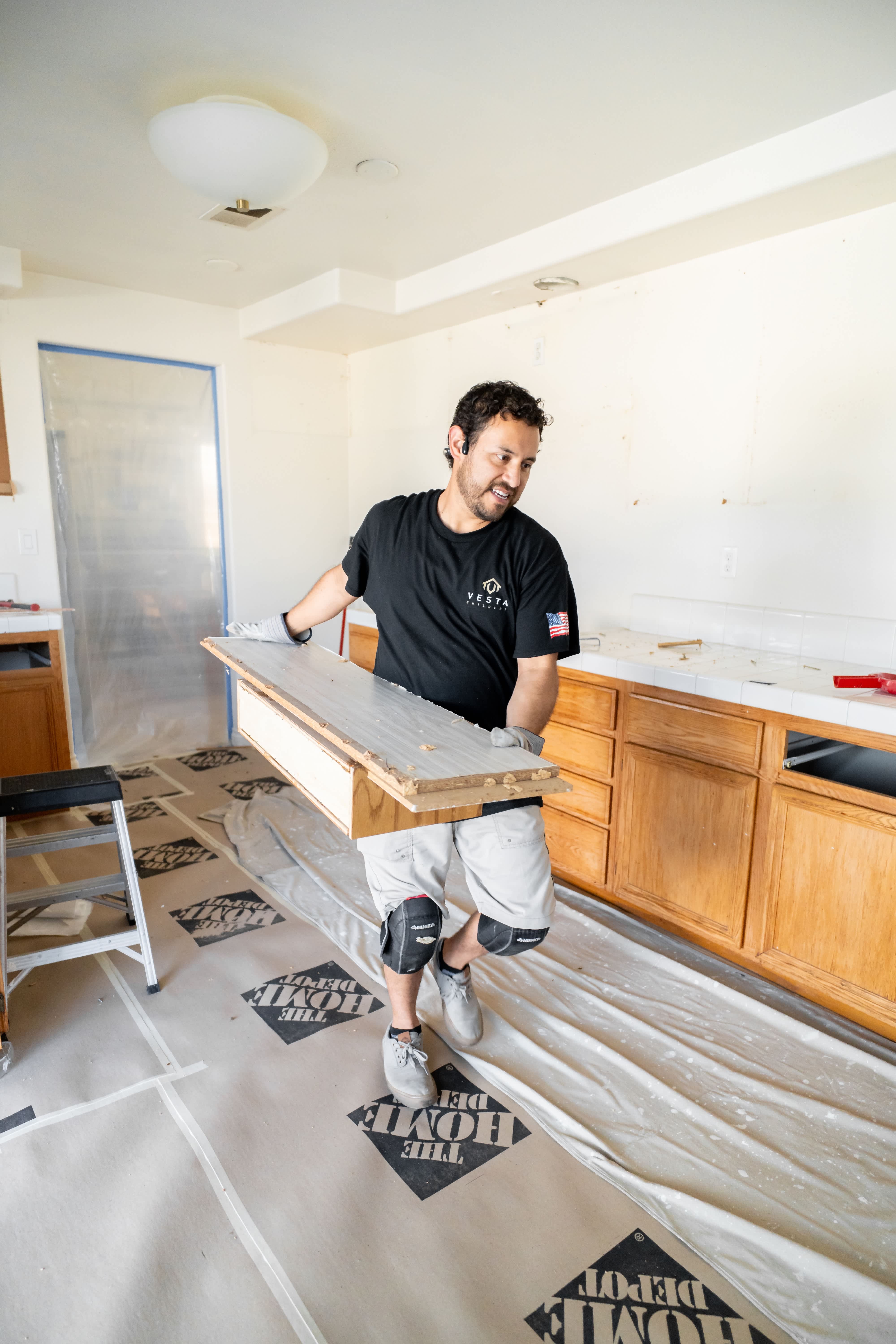Person carrying planks of wood through a demolished kitchen