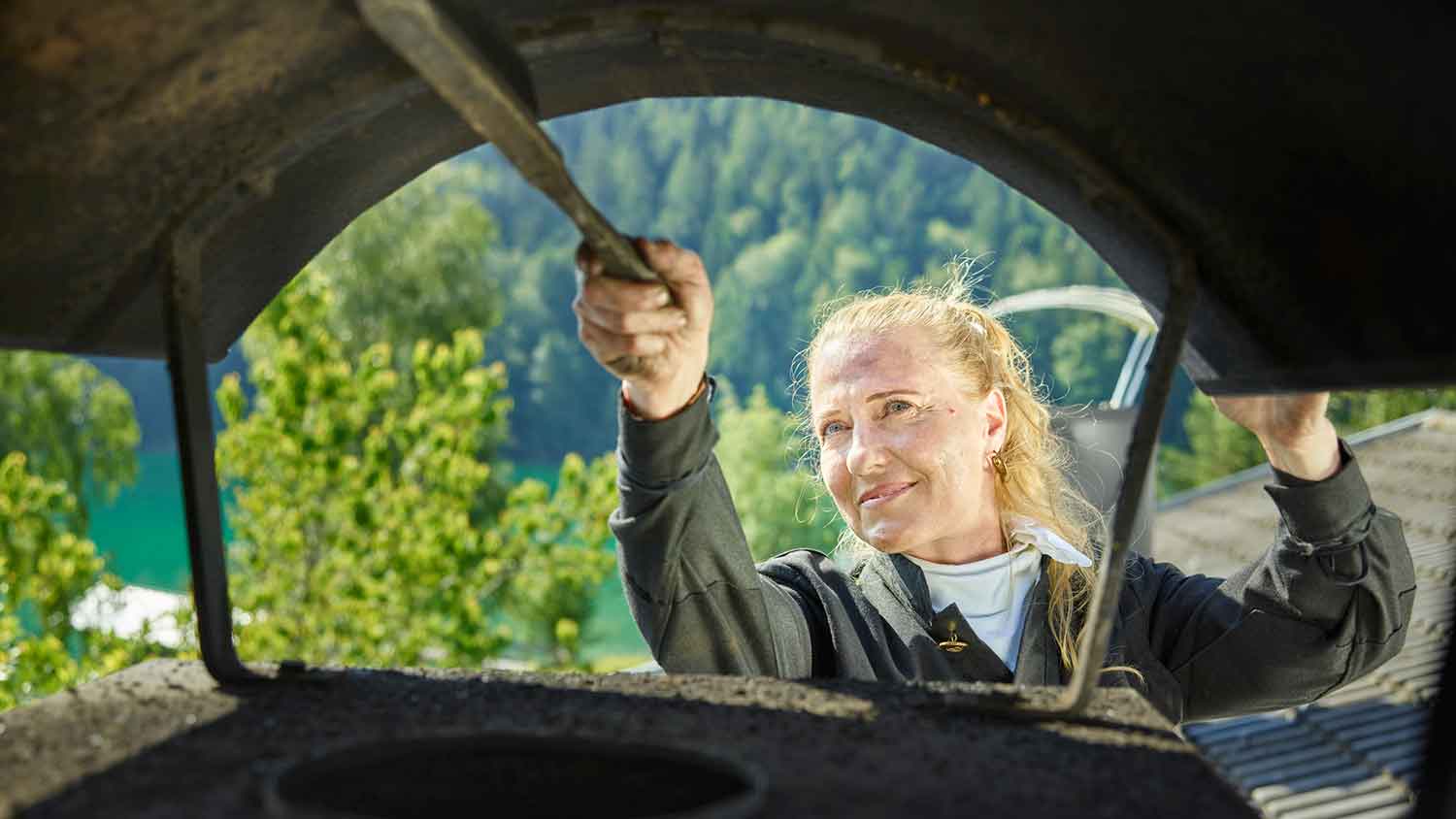 Female sweeper cleaning a chimney with a brush